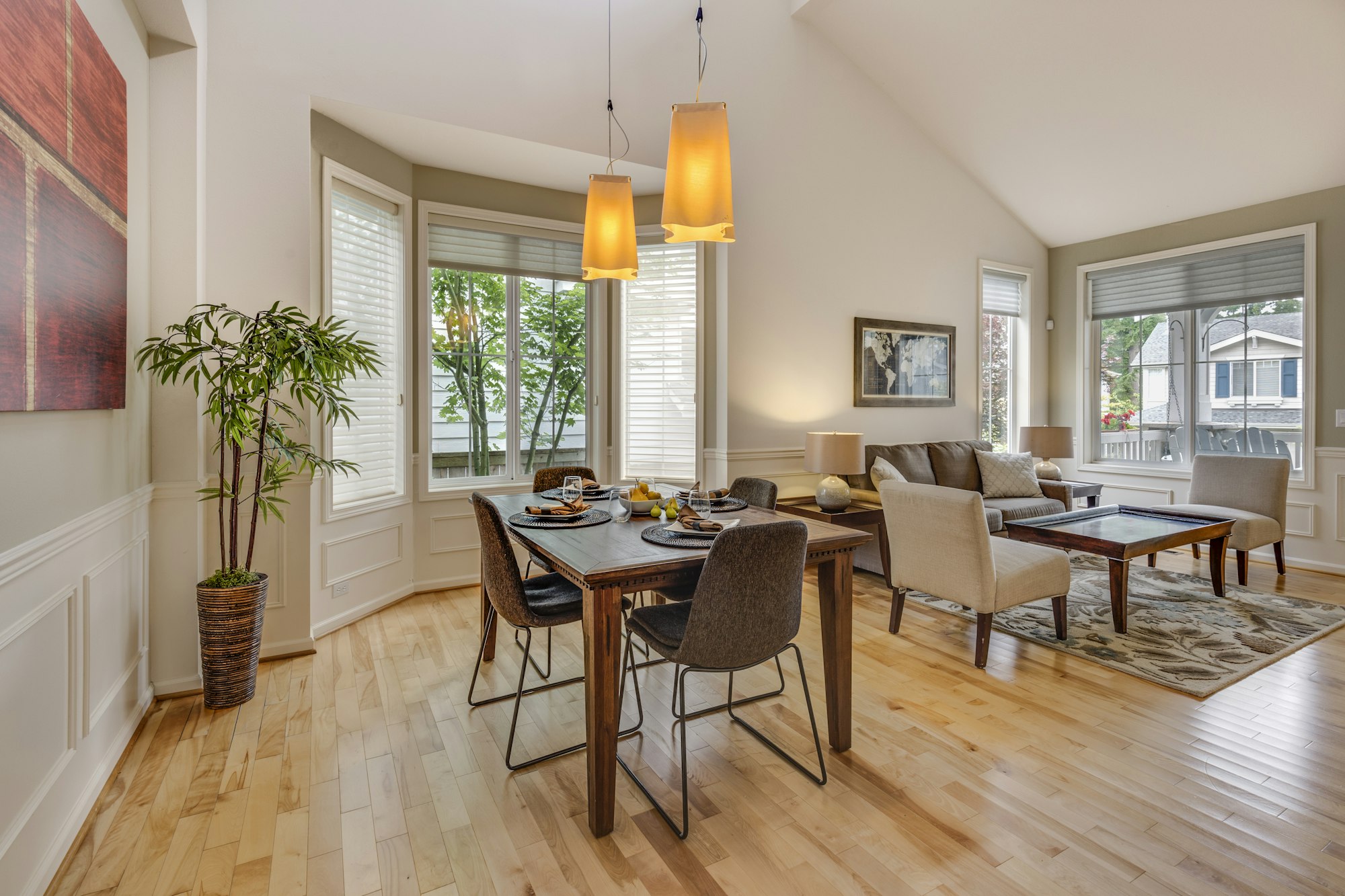 Dining area with pendant lights, vaulted ceiling, and hardwood floors.